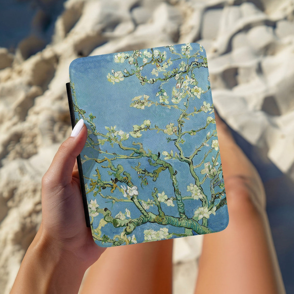 Hands holding the Almond Blossom Kindle case outdoors