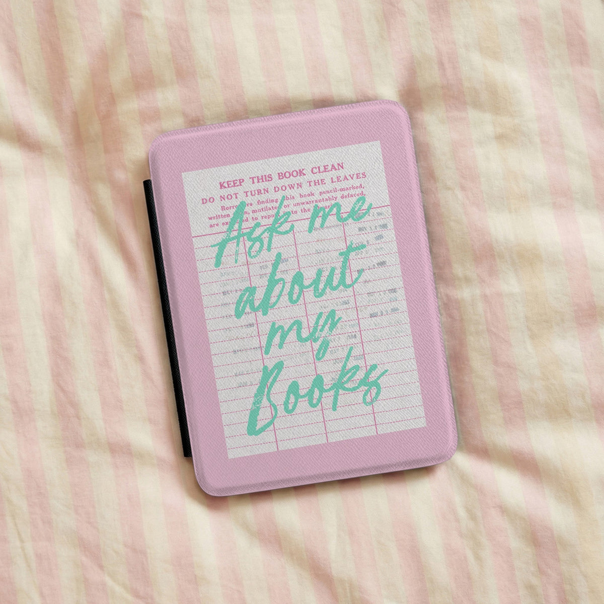 Ask Me About My Books Kindle case on a striped bedspread
