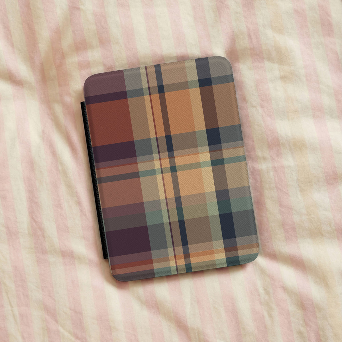 Autumn Plaid Kindle case lying on striped bedding