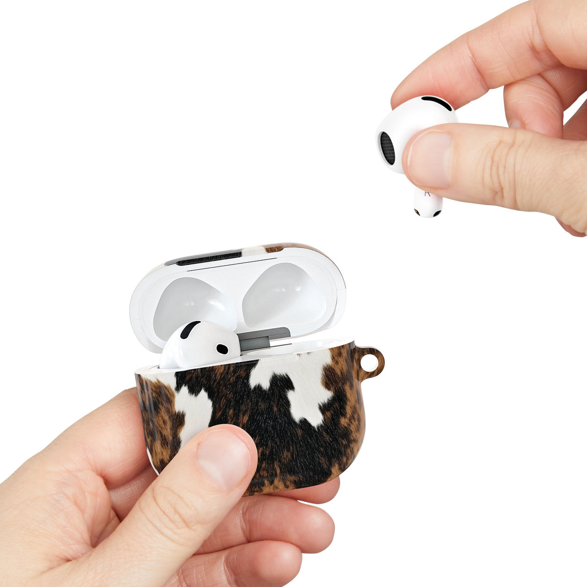 Hand taking an AirPod from the open Brown Cow Print AirPods case