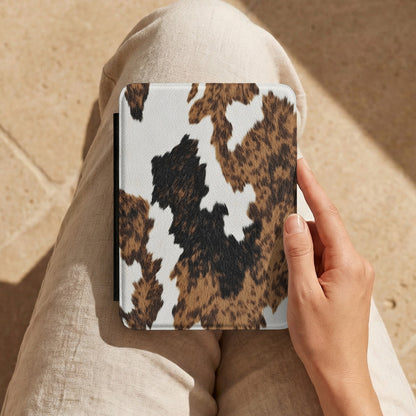 Brown Cow Print Kindle case held on a lap in cream trousers