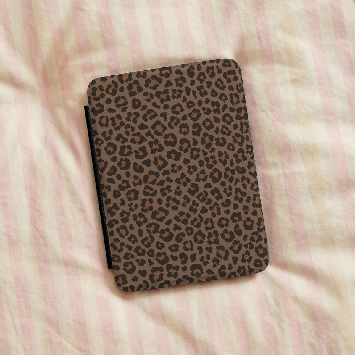 Brown leopard print Kindle case on pink striped bed linen