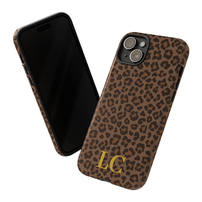 Brown leopard print tough phone case with gold initials beside an iPhone