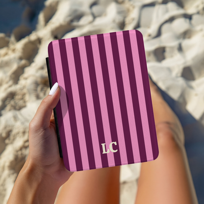 Hand holding a Burgundy Pink Cabana Stripe Kindle case with initials, outdoors