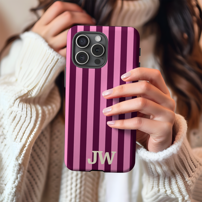Hands holding a burgundy and pink cabana stripe tough phone case with initials