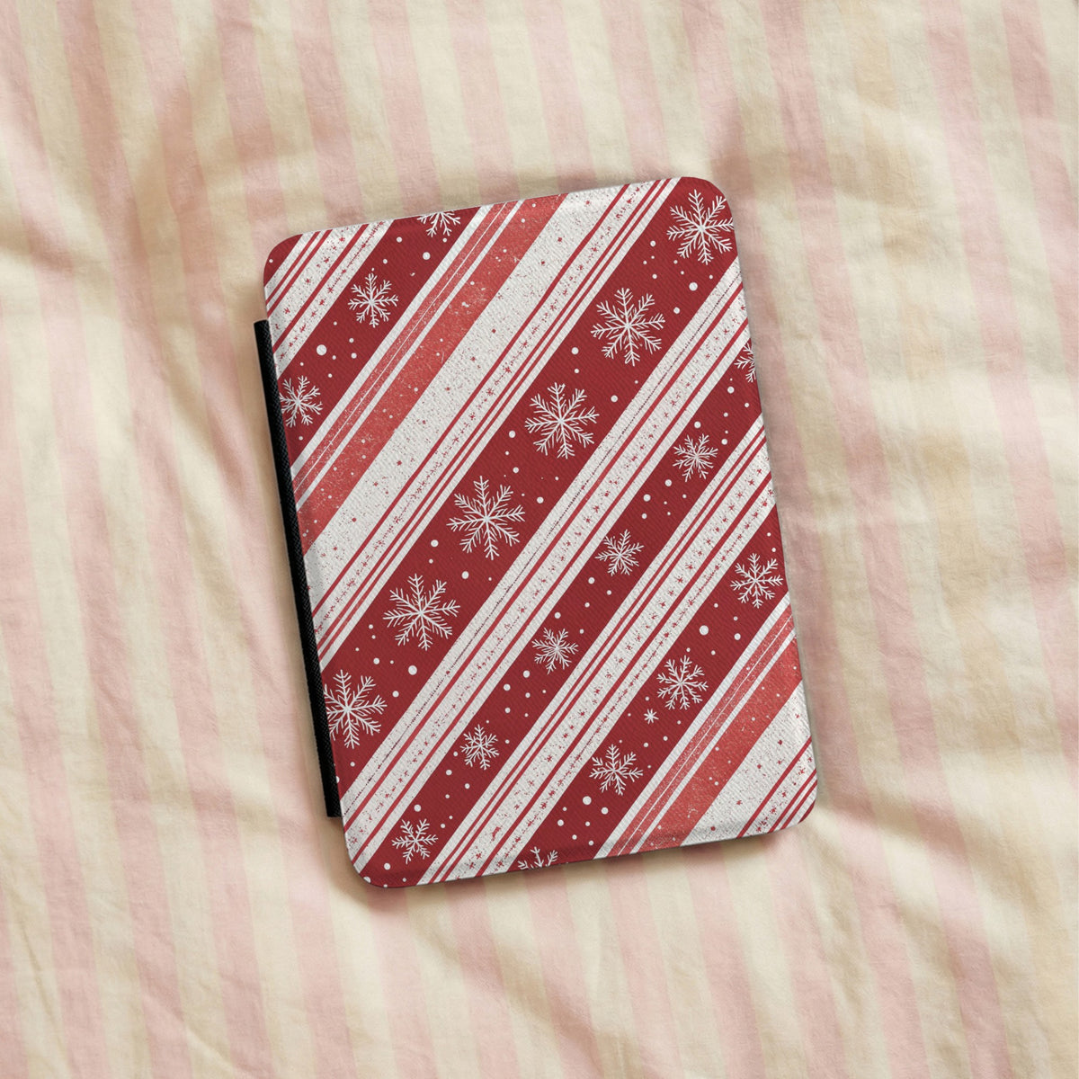 Candy Cane Snowflake Kindle case lying on pink striped bedding