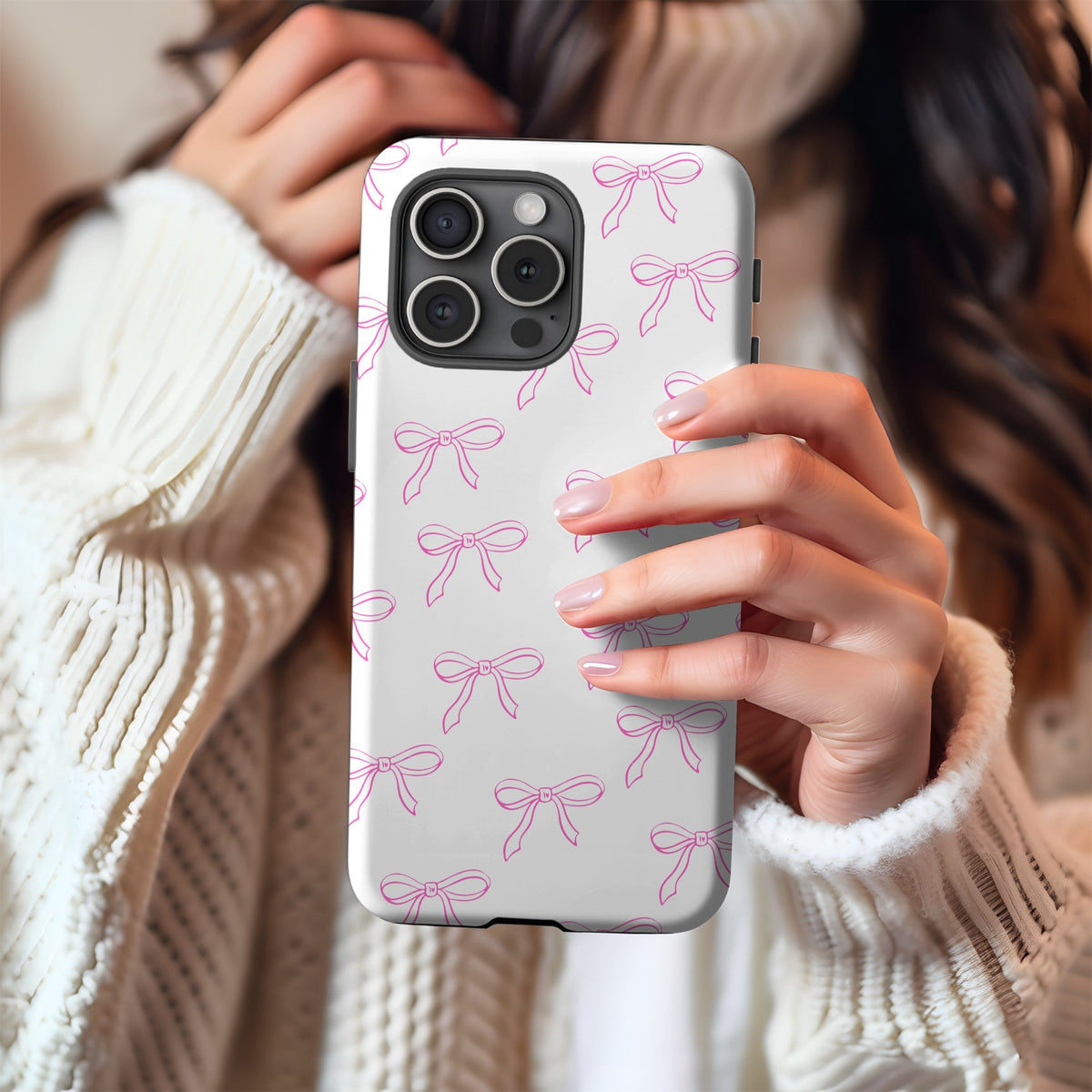 Hands in a cream knit sweater holding the Coquette Bows phone case