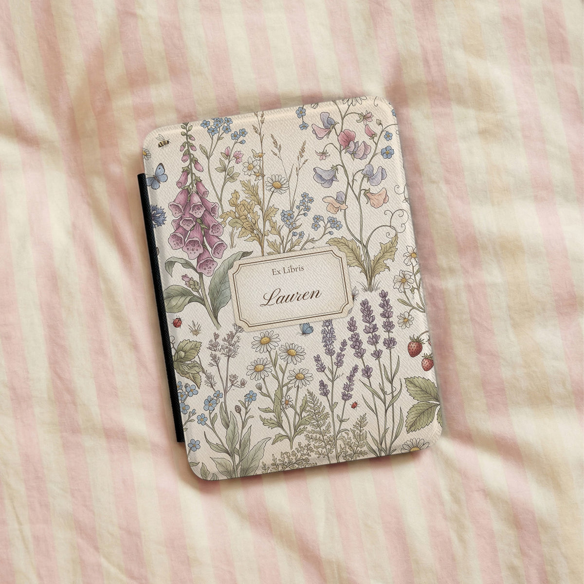 Cottage Meadow Ex Libris Kindle case lying on pink striped bedding