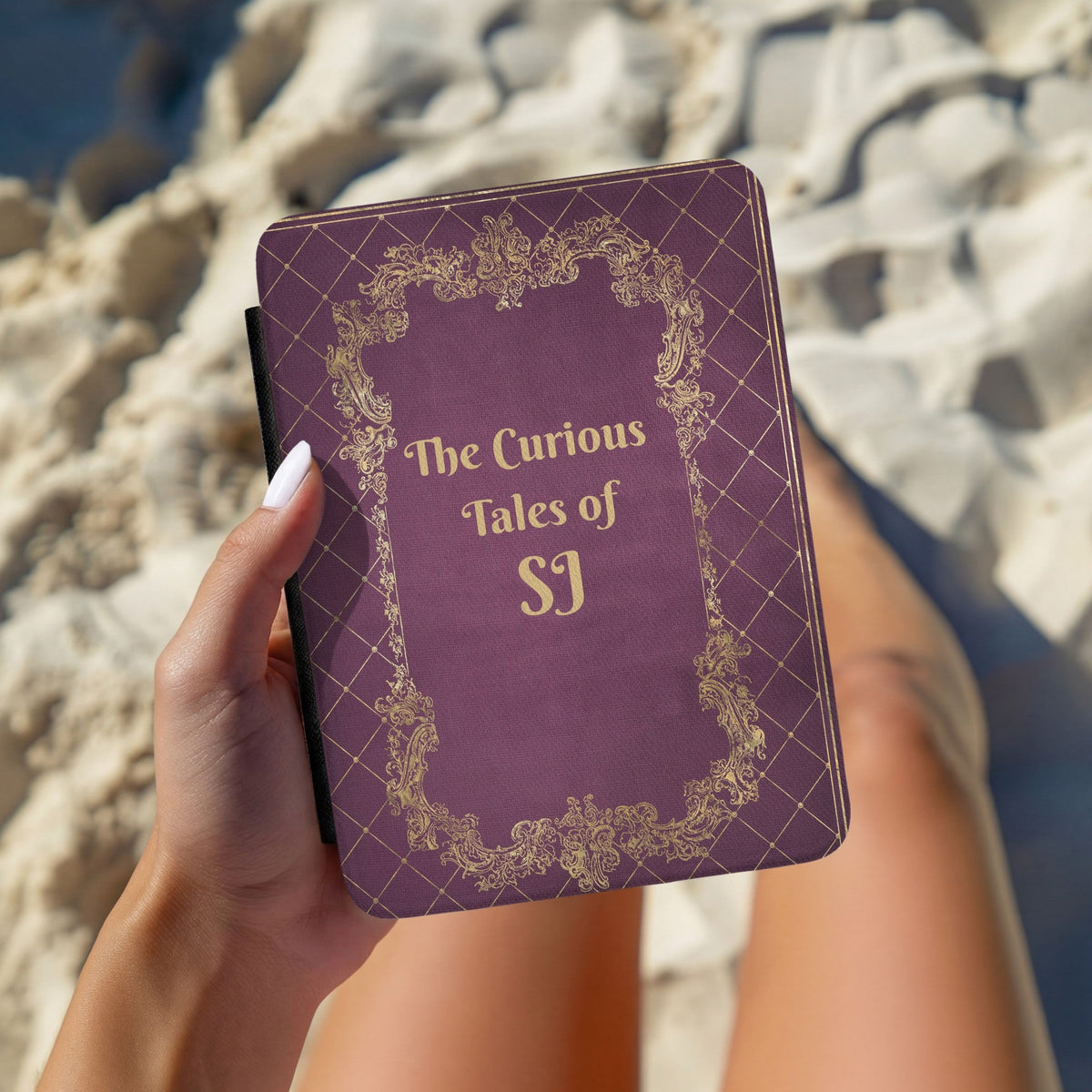Hand holding a personalised Curious Tales Kindle case outdoors