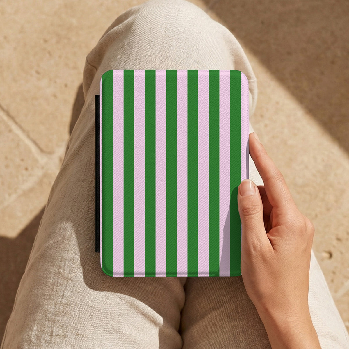 Green Cabana Stripe Kindle case held on the lap in the sun