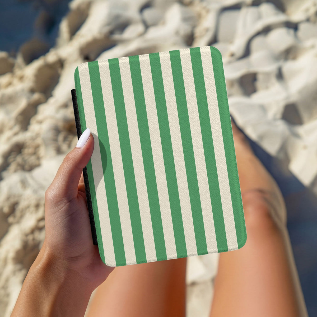 Hand holding a personalised green and cream cabana stripe Kindle case outdoors