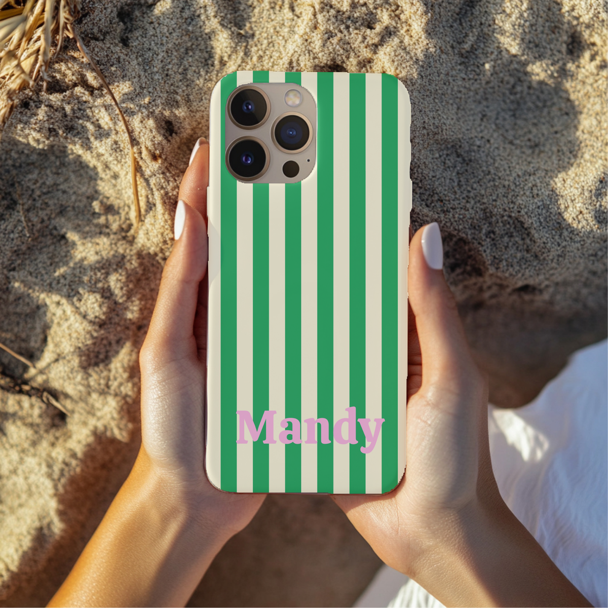 Hands holding a Green Cream Cabana Stripe phone case with a personalized name, outdoors