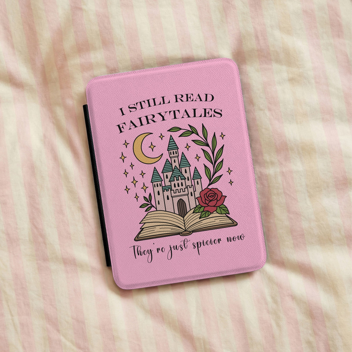 I Still Read Fairytales Kindle case lying on pink striped bedding