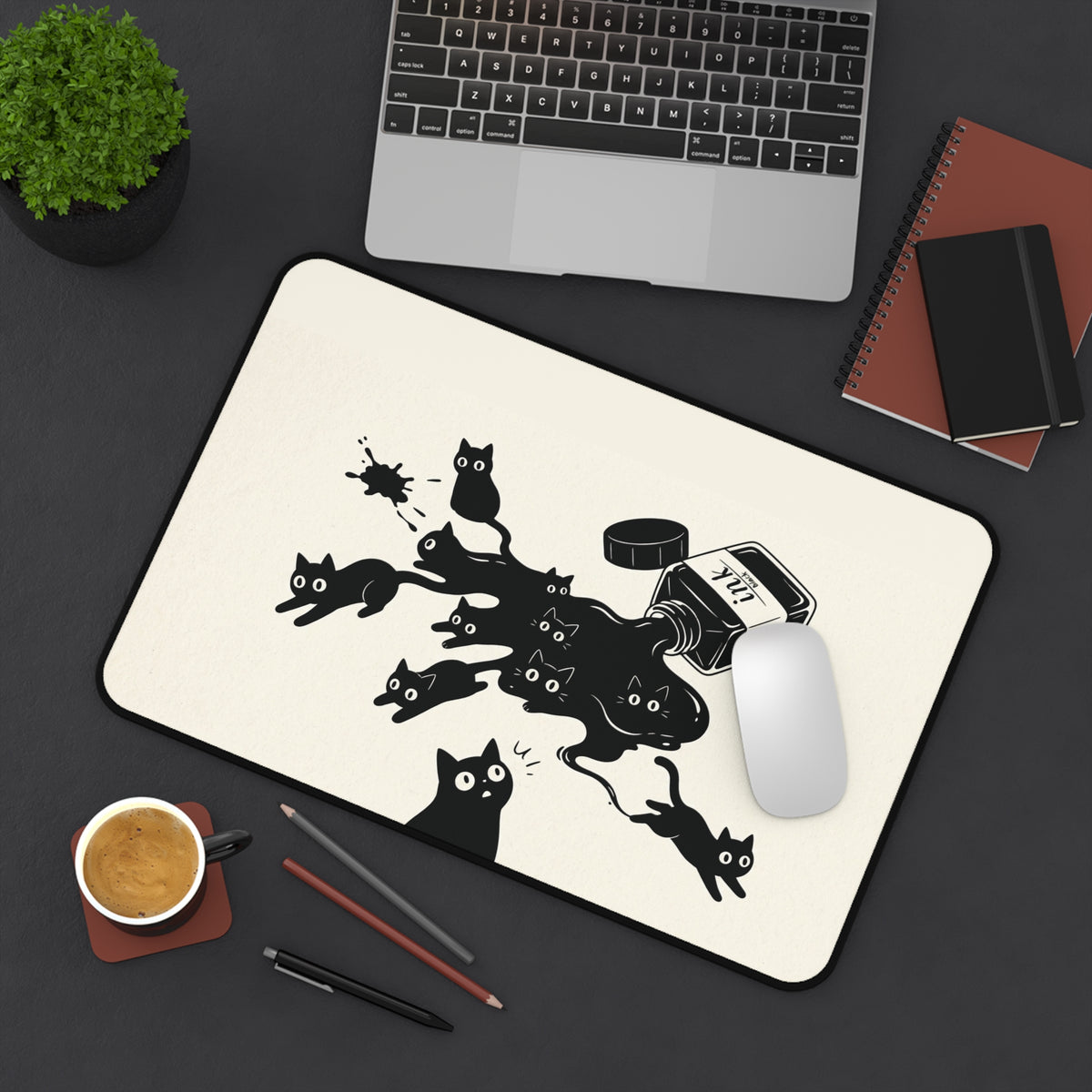 Ink Spill Cats desk mat on a dark desk with a laptop, mouse and coffee