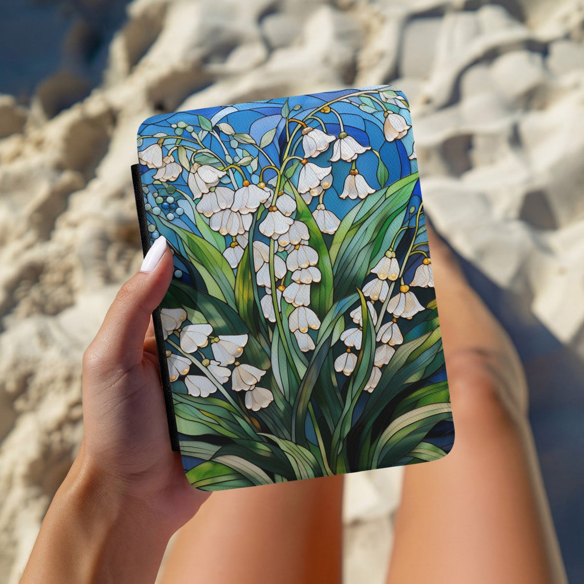 Hands holding the Lily of the Valley Kindle case outdoors