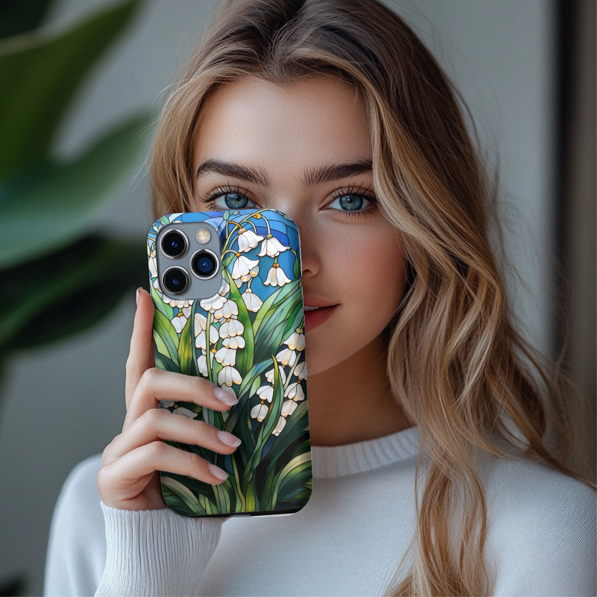 Woman holding a Lily of the Valley phone case in front of her face