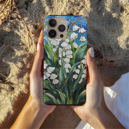 Hands holding a Lily of the Valley tough phone case over sand