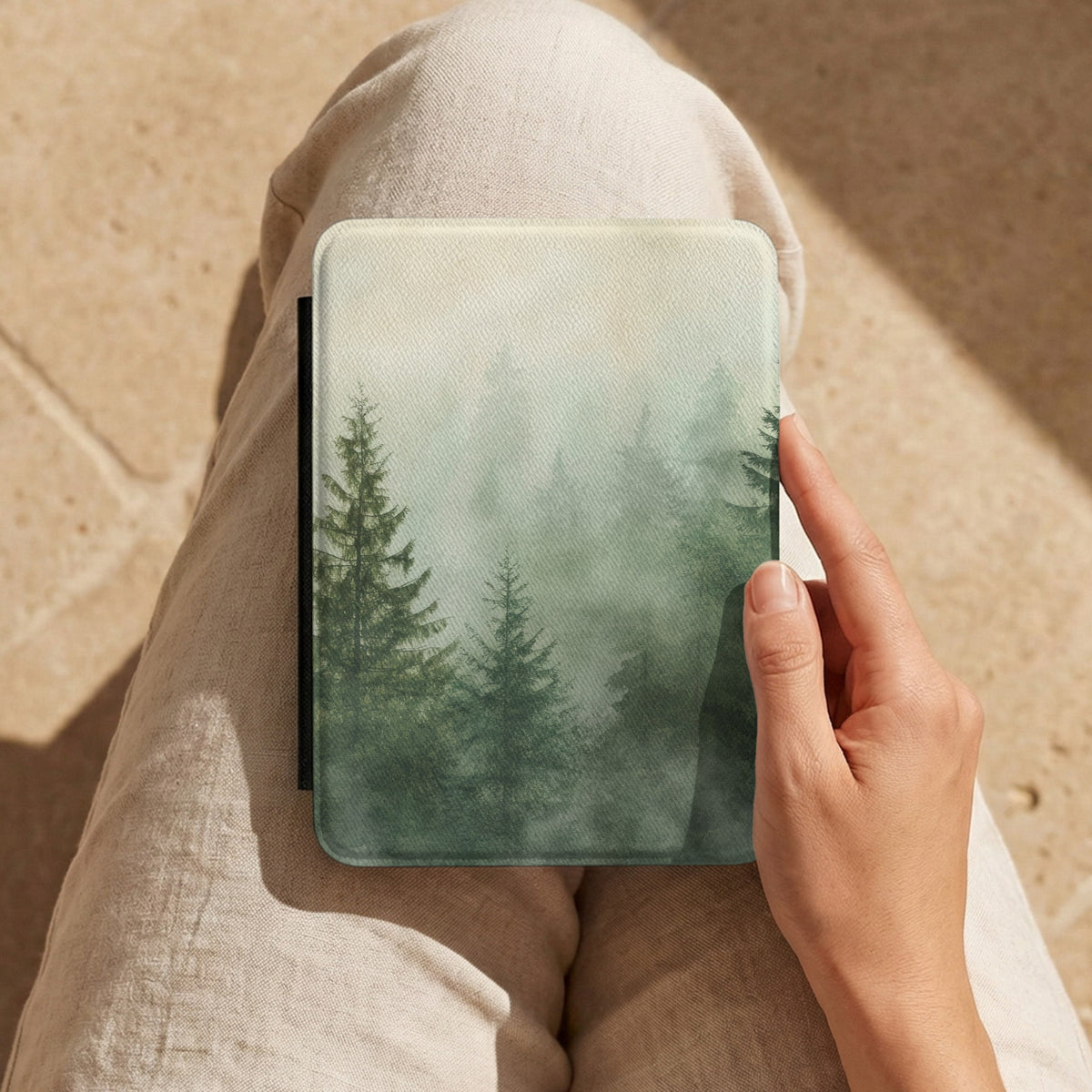 Misty Pine Forest Kindle case held on the lap while reading