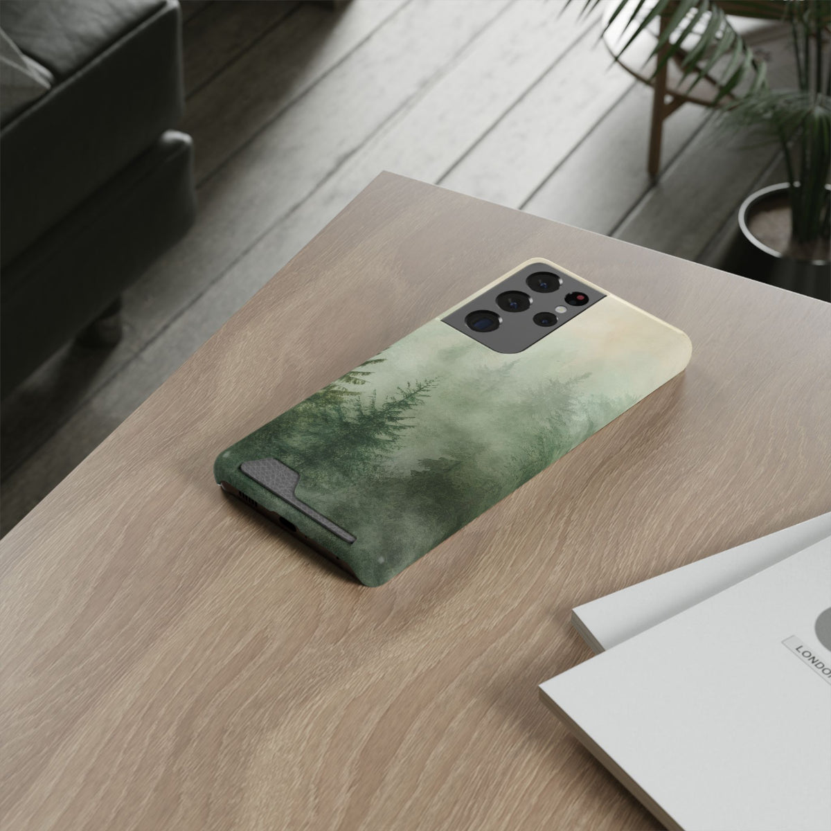 Misty Pine Forest card holder phone case lying on a wooden desk