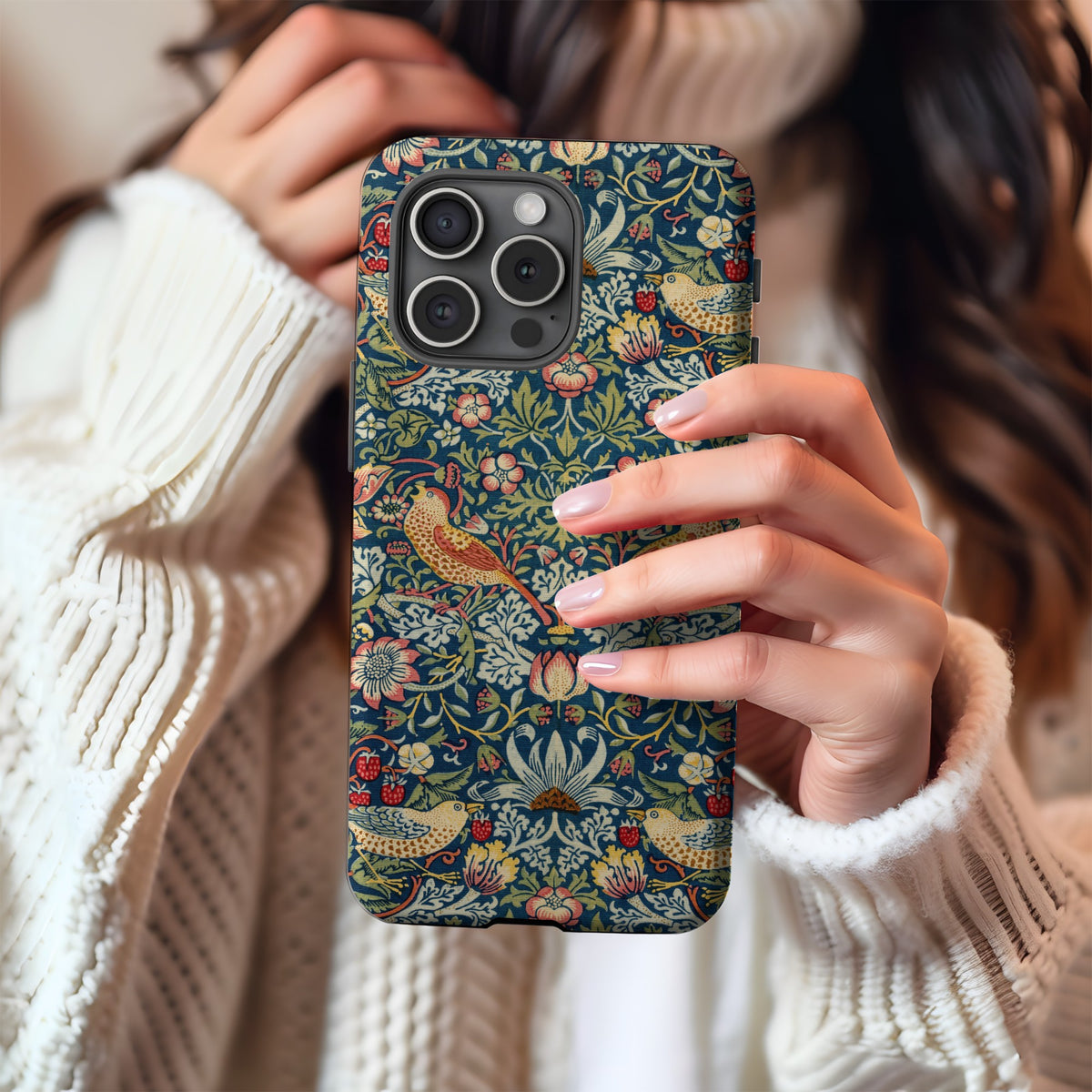 Morris Strawberry Thief tough phone case held in hand against a cream knit sweater