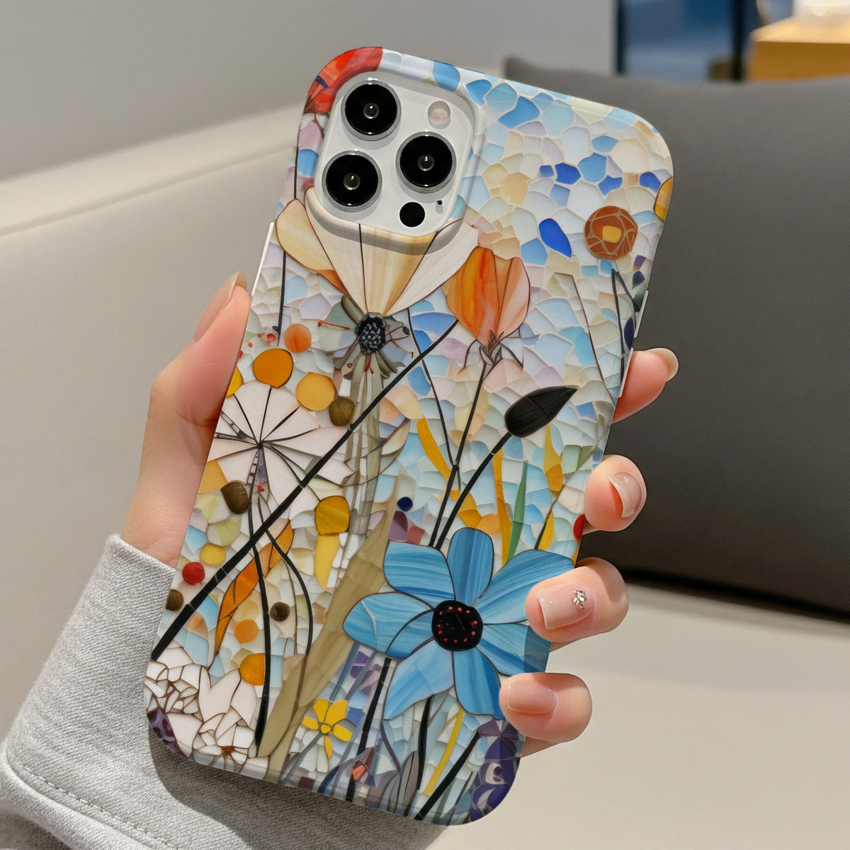 Hand holding a slim Mosaic Meadow floral phone case