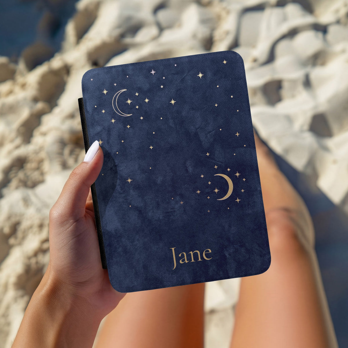 Navy Crescent Moon Kindle case with a name, held in hand over bedding