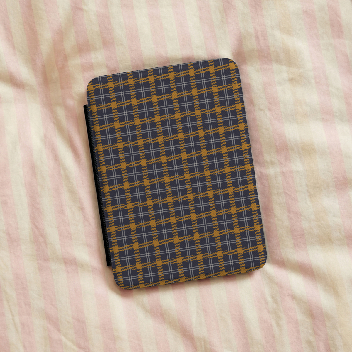 Navy ochre plaid Kindle case on striped bed linen