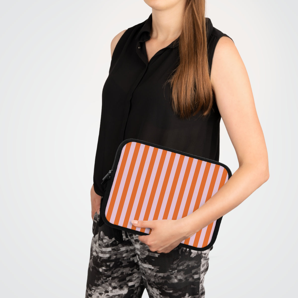 Woman carrying an orange cabana stripe laptop sleeve