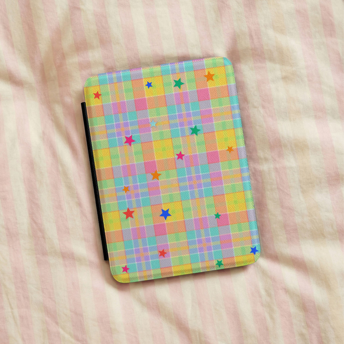 Pastel Plaid Stars Kindle case lying on pink striped bedding