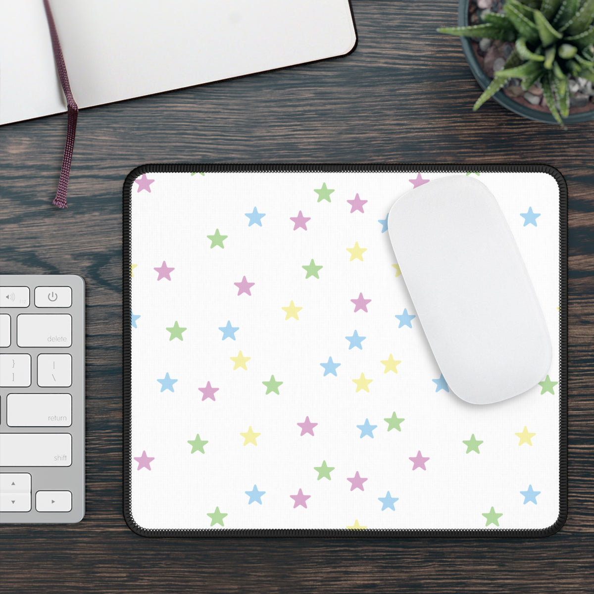 Pastel Stars mouse mat on a wooden desk with a mouse, keyboard and plant