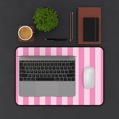 Pink cabana stripe desk mat on a dark desk with a laptop and mouse