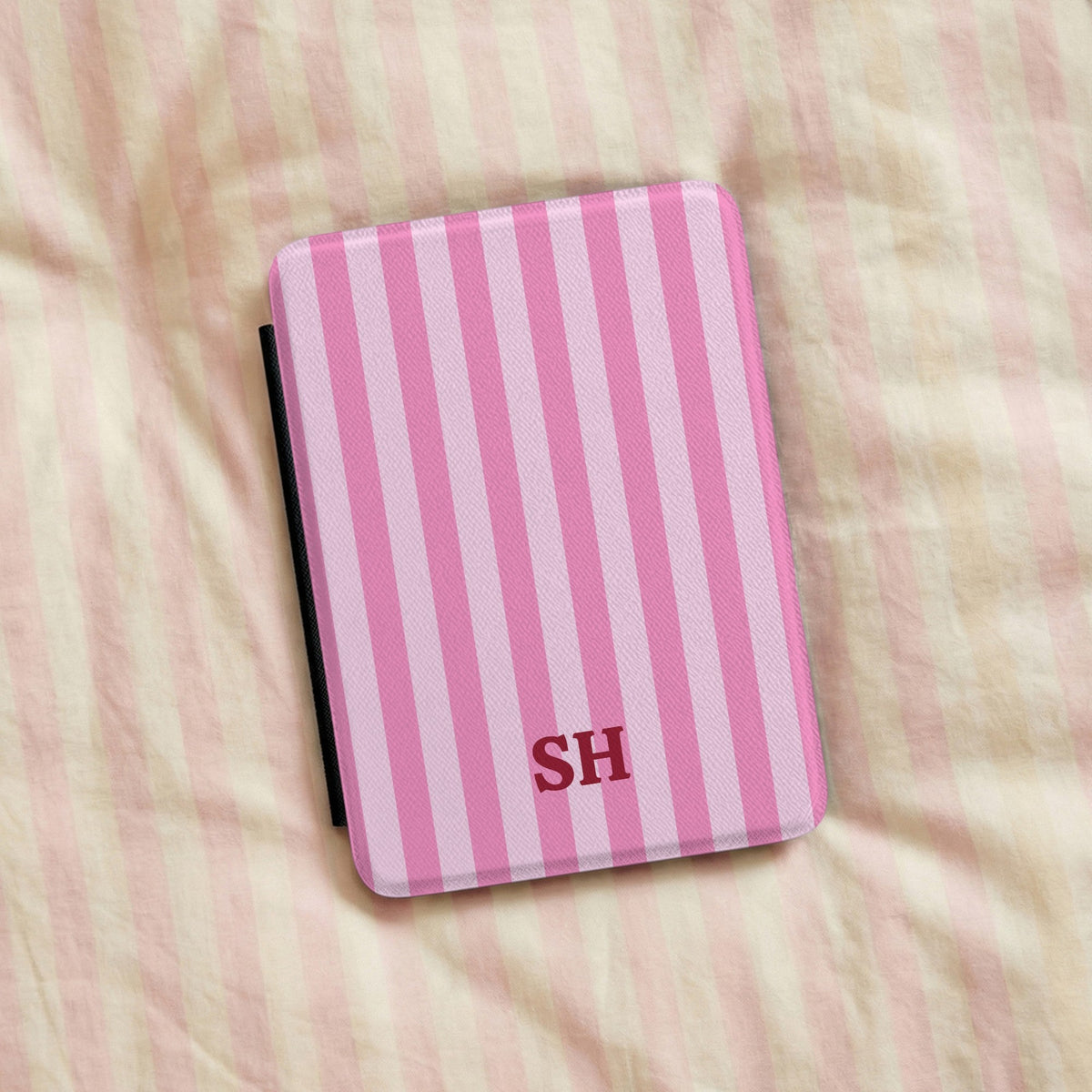 Personalised pink cabana stripe Kindle case on a bed