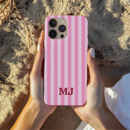 Hands holding a Pink Cabana Stripe tough phone case with initials, outdoors