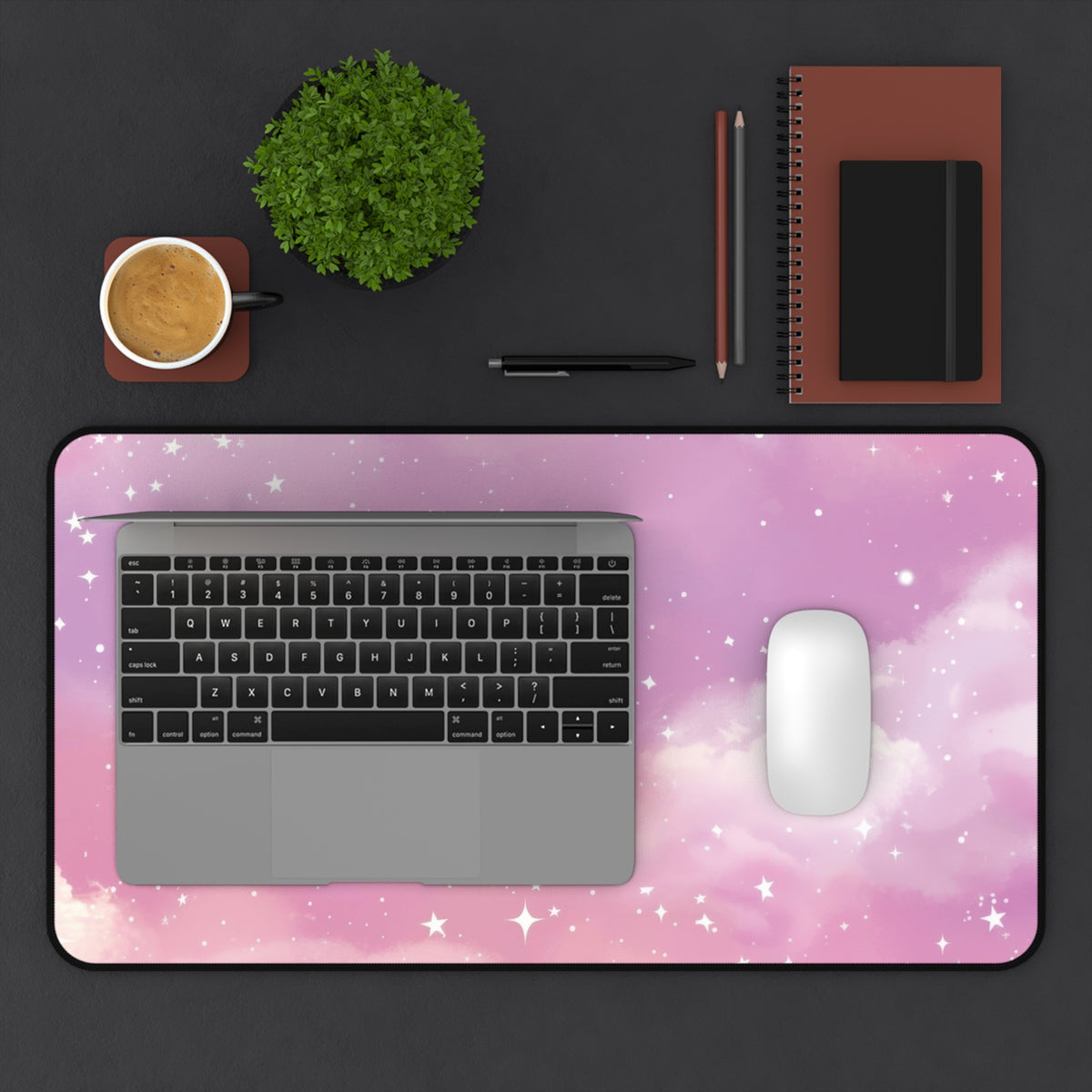 Pink Galaxy desk mat seen from above with a keyboard, notebook and coffee