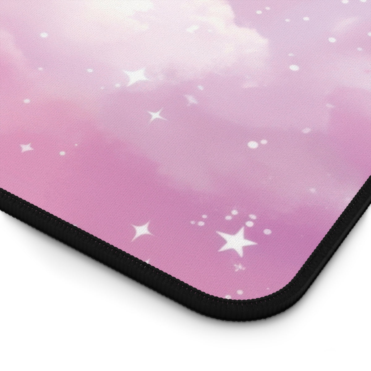 Close-up of the stitched edge and rounded corner of the Pink Galaxy desk mat