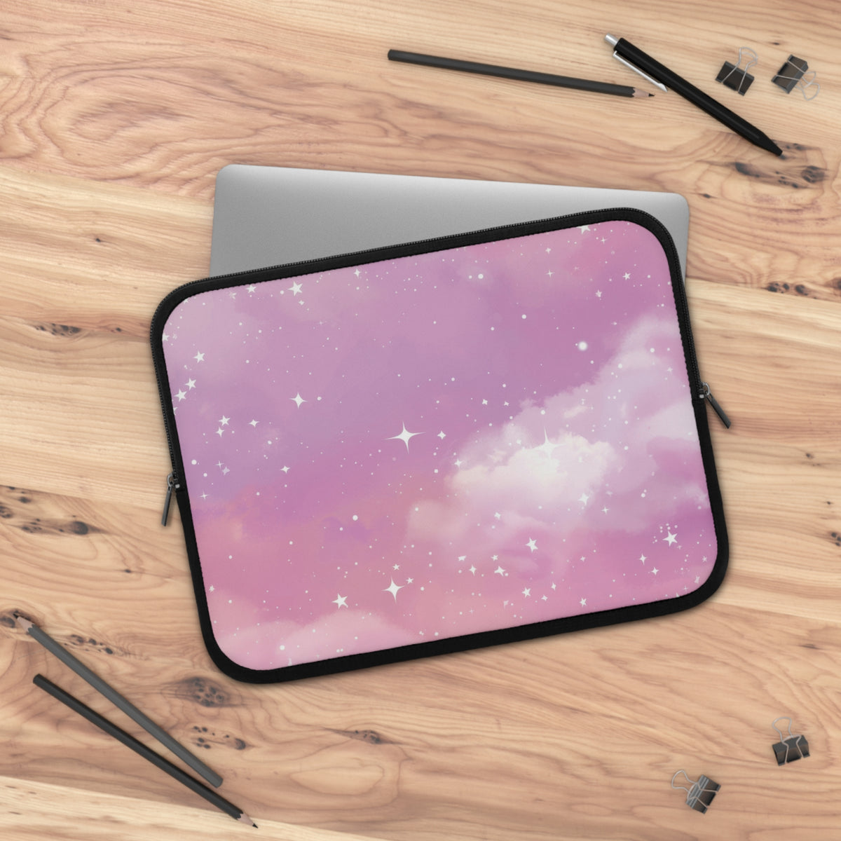 Pink Galaxy laptop sleeve on a wooden desk beside a laptop