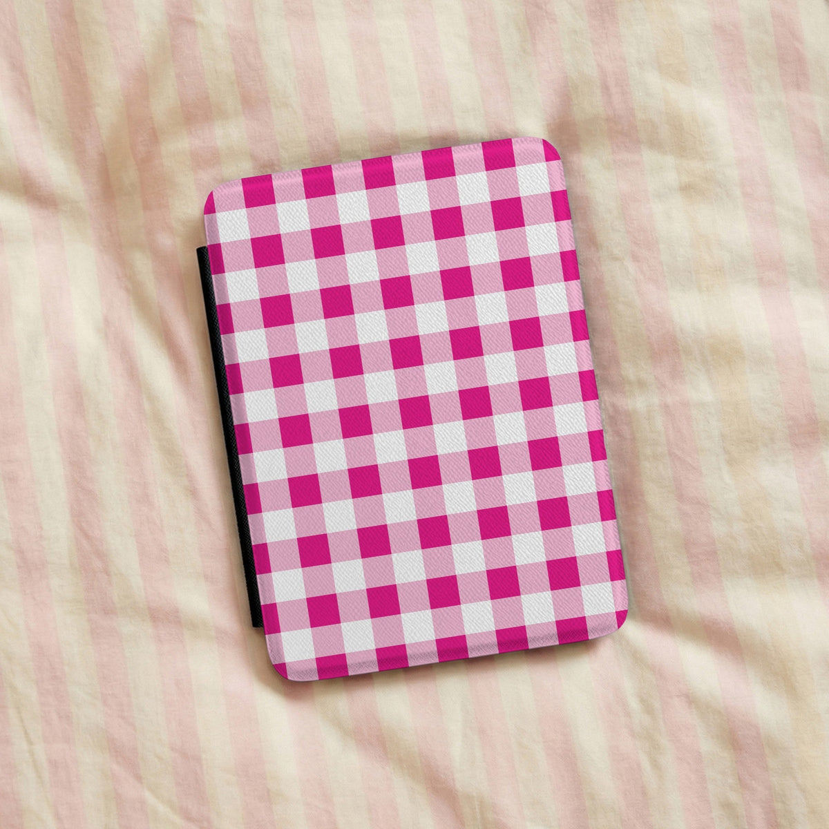 Pink gingham Kindle case on striped bed linen