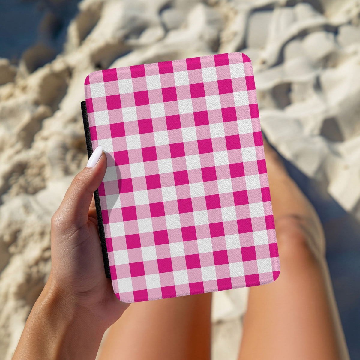 Hand holding a pink gingham Kindle case outdoors