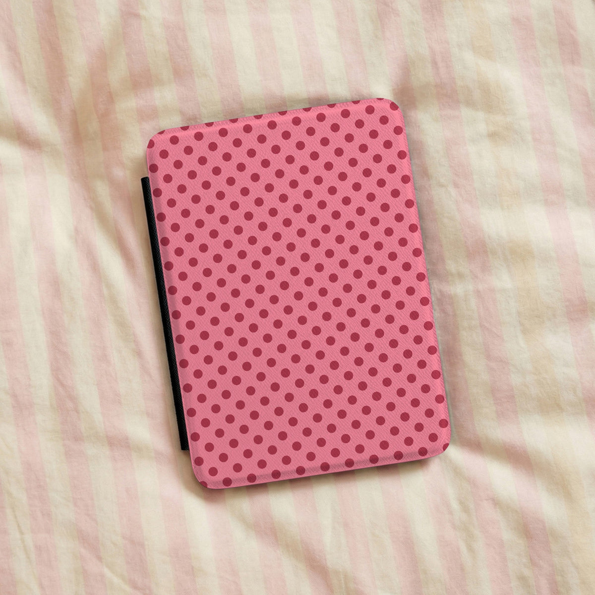 Pink polka dot Kindle case on striped bed linen