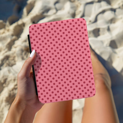 Hand holding a pink polka dot Kindle case outdoors