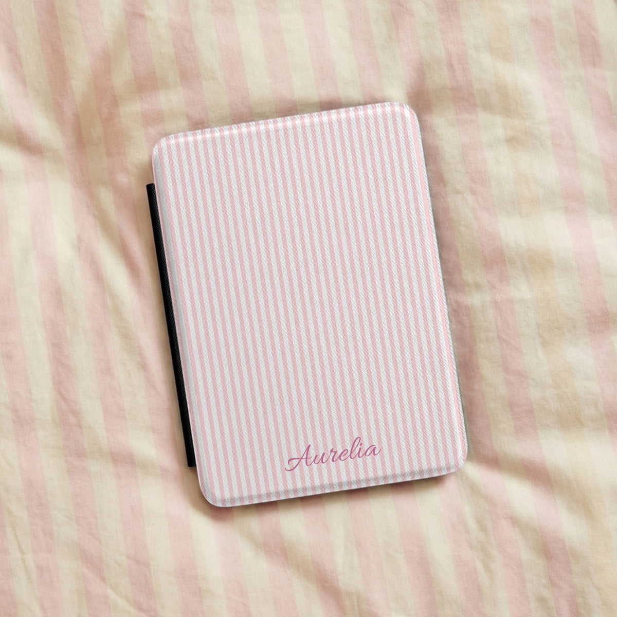 Pink Seersucker Kindle case resting on striped bedding