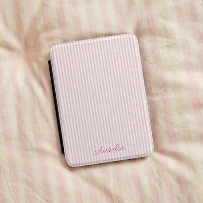 Pink Seersucker Kindle case resting on striped bedding