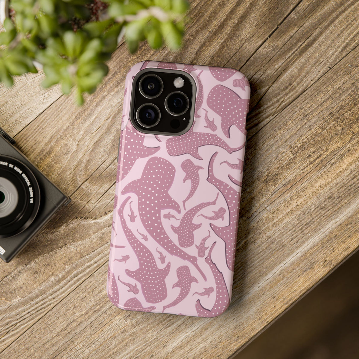 Pink Whale Shark tough magnetic phone case on a wooden table next to a plant