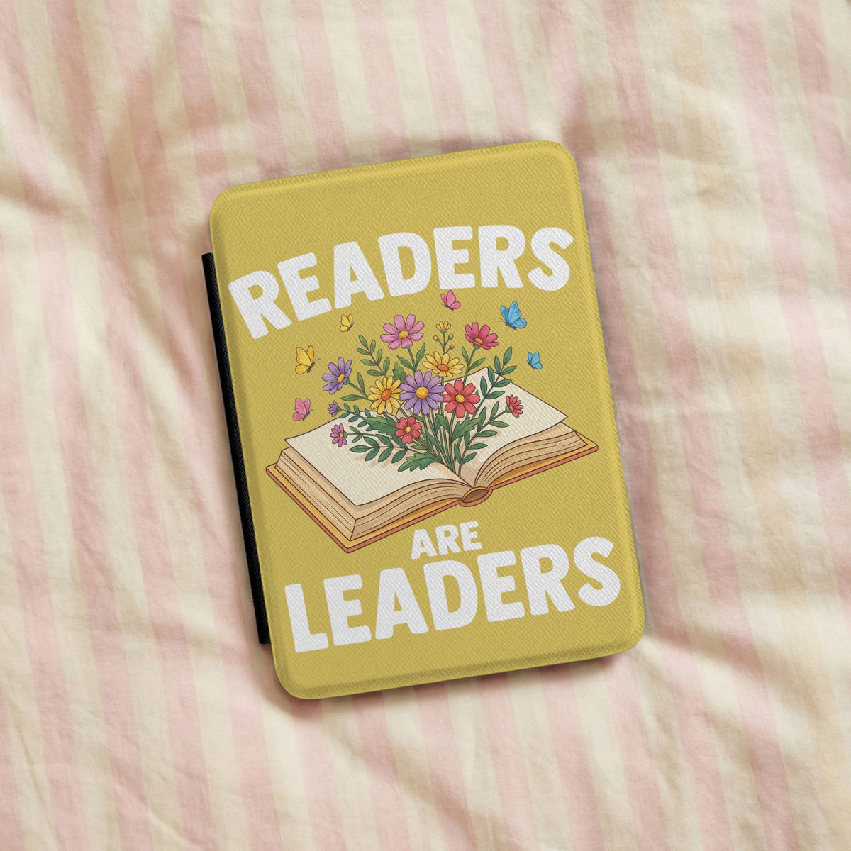Readers Are Leaders Kindle case lying on pink striped bedding