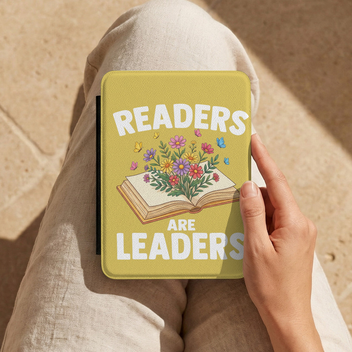 Readers Are Leaders Kindle case held on a lap in warm sunlight