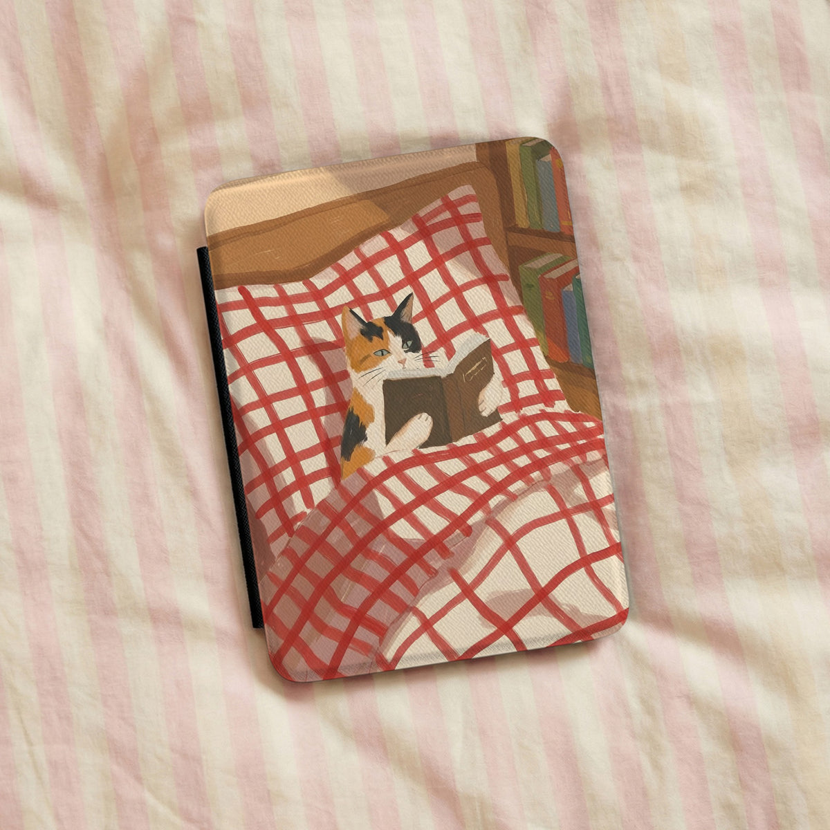 Reading Cat Kindle case lying on pink striped bedding