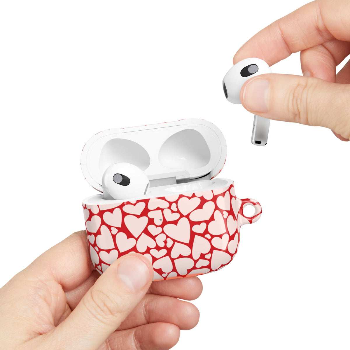 Red hearts AirPods case held in hand while taking out an earbud