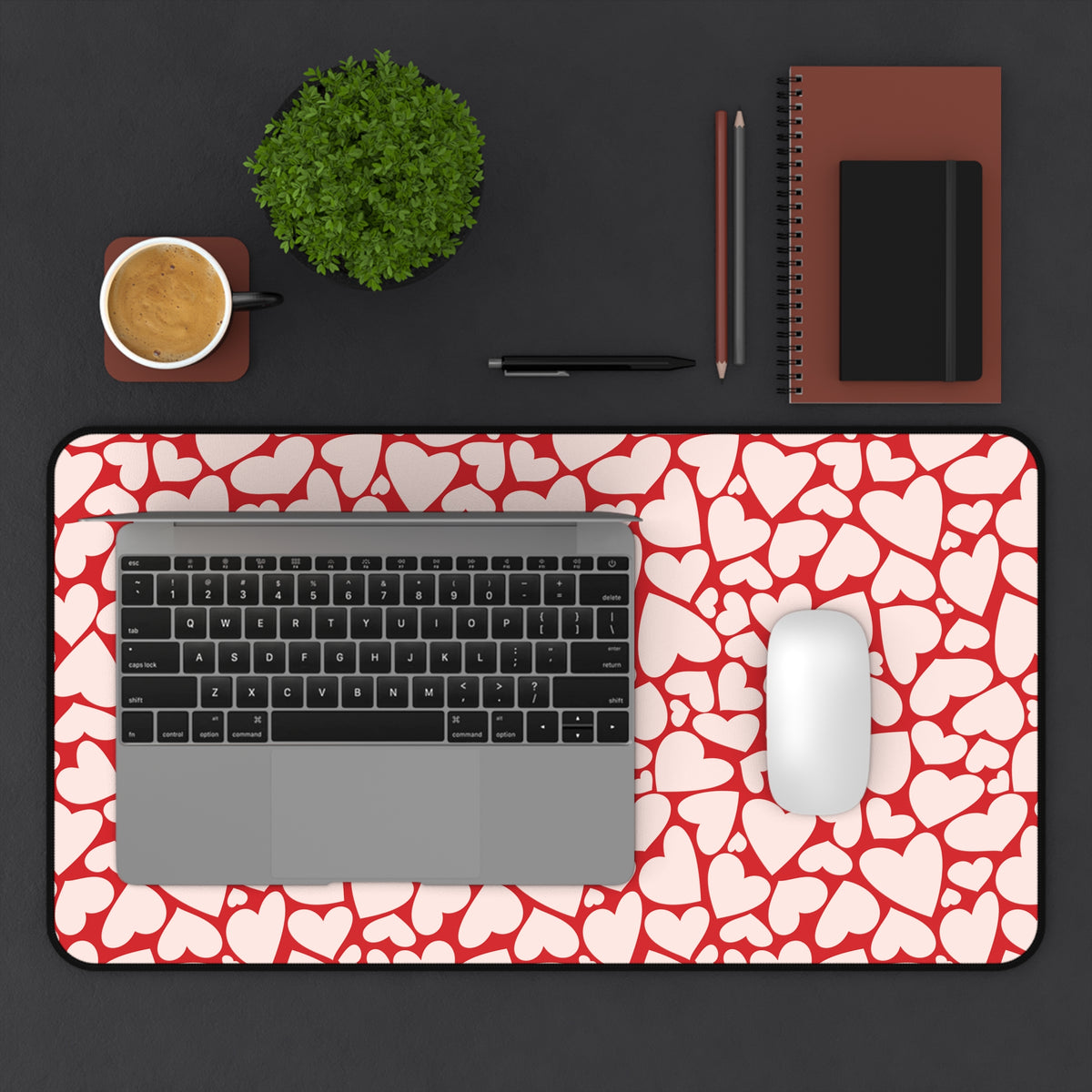 Red hearts desk mat on a dark desk with a laptop, mouse and coffee