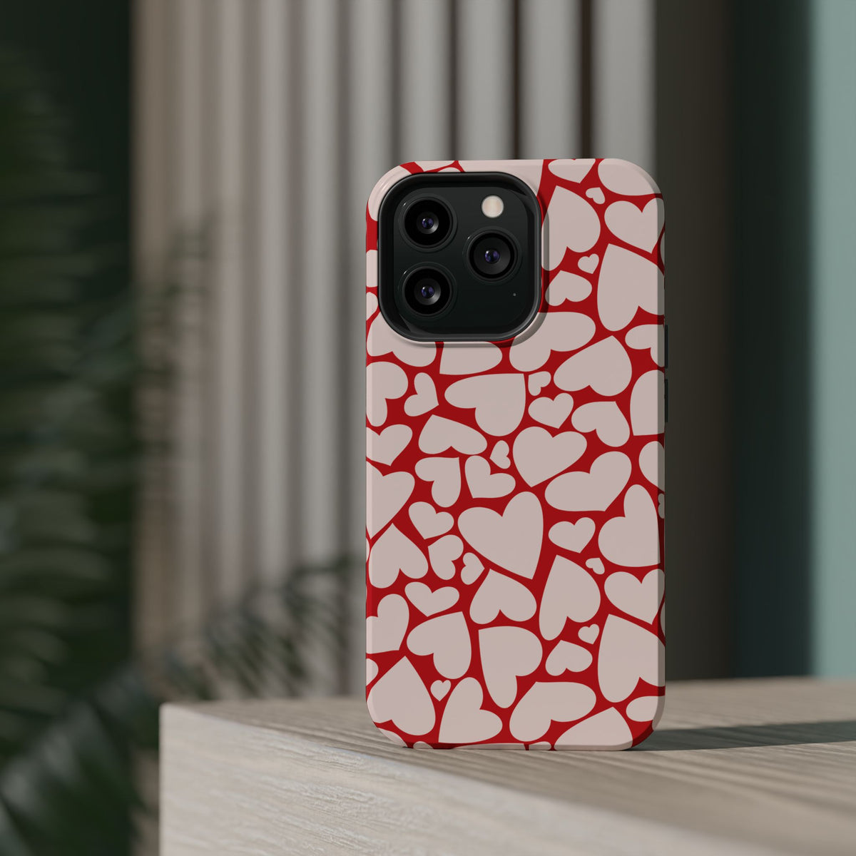 Red Hearts MagSafe phone case on a phone standing on a wooden shelf