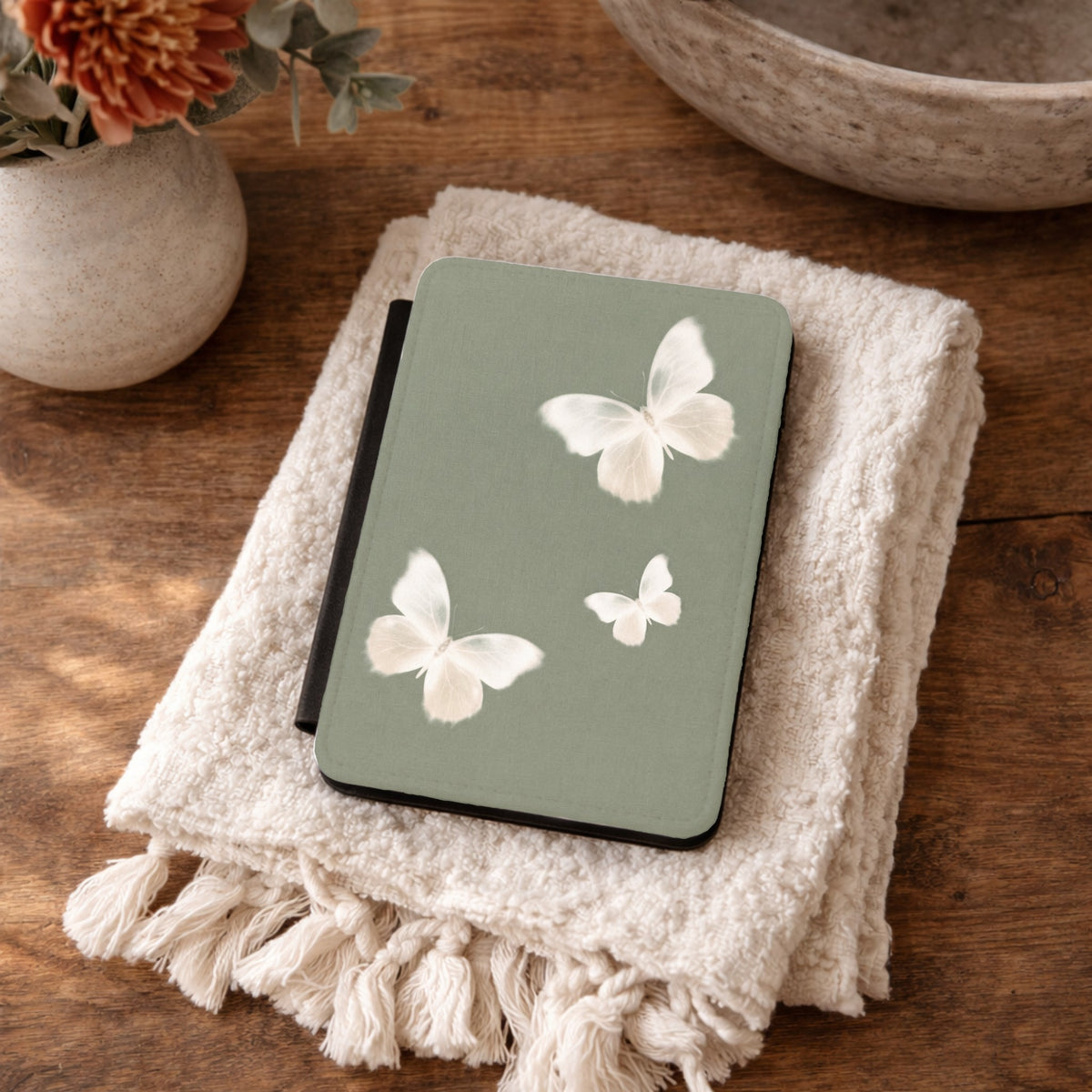 Sage Butterfly Kindle case resting on a folded cream towel